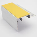 Heavy duty 56mm x 55mm aluminium tile-in stair nosing on a plain studio background showing the mill finish body, hollow chambers, perforated tiling leg and yellow PVC insert
