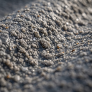 Macro close-up of the silicon carbide grit surface of an anti-slip GRP sheet with water droplets on it