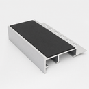Aluminium tile-in stair edge trim on a plain studio background showing the black PVC insert, slotted anchoring leg and hollow chambers
