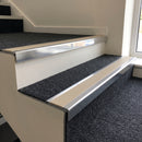 Bright polished aluminium stair nosing with Beige insert fitted to charcoal carpet tile on an office stair