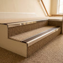 Bright polished aluminium stair nosing with Brown insert fitted to oatmeal carpet on a solicitors office stair