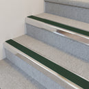 Bright polished aluminium stair nosing with Dark Green insert fitted to pale stone-grey carpet on a clubhouse stair