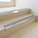 Bright polished aluminium stair nosing with Mid Grey insert fitted to pale cream carpet tile on a business park reception stair