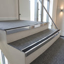 Bright polished aluminium stair nosing with Premium Black insert fitted to mid-grey carpet tile on a conference centre stair
