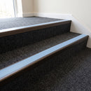 Dark bronze aluminium stair nosing with Aura insert fitted to charcoal carpet tile on a medical centre stair