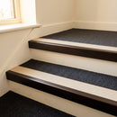 Dark bronze aluminium stair nosing with Beige insert fitted to dark charcoal carpet on a hotel stair