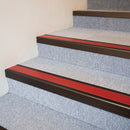 Dark bronze aluminium stair nosing with Red insert fitted to pale grey carpet tile on a theatre circle stair