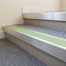Mill finish aluminium stair nosing with Apple Green insert fitted to grey carpet on a sixth form college stair