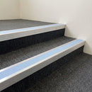 Mill finish aluminium stair nosing with Aura insert fitted to charcoal carpet tile on a health centre stair