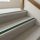 Mill finish aluminium stair nosing with Dark Green insert fitted to pale stone-grey carpet on a town hall stair