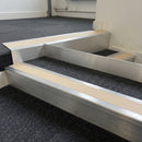 Mill finish aluminium stair nosing with Sahara insert fitted to dark charcoal carpet tile on a retail stockroom stair