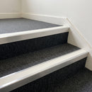 Mill finish aluminium stair nosing with White insert fitted to dark grey carpet tile on an apartment block stair