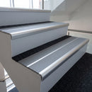 Bright polished aluminium bullnose stair nosing with twin mid grey inserts fitted on an office stairwell step