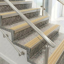 Raked back nosings with ivory ribbed inserts on mottled stone steps between stainless handrails