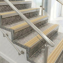 Raked back nosings with ivory ribbed inserts on mottled stone steps between stainless handrails