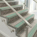 Raked back nosings with jade green ribbed inserts on mottled stone steps between stainless handrails