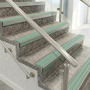 Raked back nosings with jade green ribbed inserts on mottled stone steps between stainless handrails
