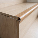 Close-up of the oak push-in stair nosing on a step edge with the laminate tread board pushed into the channel