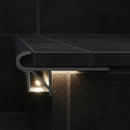 Close-up of LED stair nosing channel glowing with warm white LED light on dark porcelain tile step edge
