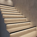 Tiled staircase with matt black aluminium LED stair nosings, warm LED glow lighting each riser