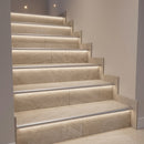 Tiled staircase with slim silver aluminium LED stair nosings flush at each tread edge, warm LED light washing the risers