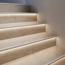 Stone-effect tiled stairs with white LED stair nosings, soft warm light washing down each riser