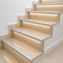 Silver anodised aluminium LED stair nosing profiles with warm white LED strip lighting on a limestone staircase