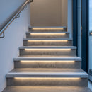 Light-down LED stair nosings with white inserts on concrete office stairs, light washing down each riser