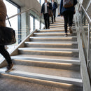 Light-out LED stair nosings with light textured inserts on a busy public building staircase, a line of light at every step edge