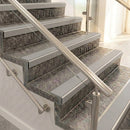 Raked back nosings with smooth light grey inserts on mottled stone steps between stainless handrails