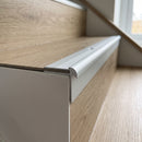 Close-up of silver aluminium stair nosing with a 5mm LVT plank sitting flush behind the 7mm lip