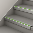 Mid grey and green insert stair nosings fitted to two pale grey steps against a white stringer wall