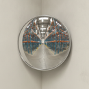 Convex stainless steel safety mirror mounted at a warehouse aisle corner reflecting the pallet racking and floor for blind-corner visibility