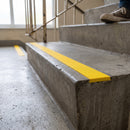 Yellow dovetail non-slip stair tread insert set into a concrete step