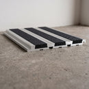 Aluminium 82.5mm carborundum stair tread extender in mill finish with black carborundum anti-slip insert, fitted to a concrete step