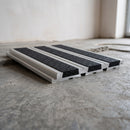 Aluminium 82.5mm carborundum stair tread extender in satin finish with black carborundum anti-slip insert, fitted to a concrete step