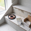 Reel of natural white COB LED tape on a freshly tiled porcelain stair tread during a lit staircase installation