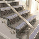 Raked back nosings with nimbus lilac-grey ribbed inserts on mottled stone steps between stainless handrails