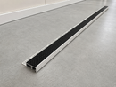 Full length of the aluminium tile-in stair nosing with black insert and perforated tiling flange, laid on a floor