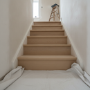 Unfinished raw solid oak stair nosing fitted during a staircase renovation with dust sheets on the floor