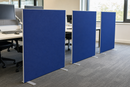 Royal blue floor standing partition screens dividing desks in an open plan office