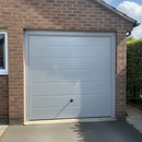 Grey gloss paint freshly applied to an up-and-over garage door on a UK house, giving a durable weatherproof finish
