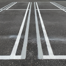 Yellow line marking paint freshly applied to car park bay lines on UK tarmac, sharp and highly visible