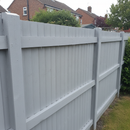 Sage green acrylic paint freshly applied to a garden shed and fence panels in a UK back garden