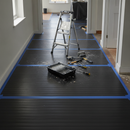 Black Correx floor protection sheets laid across a hallway floor during a home renovation with a stepladder and paint tray on top