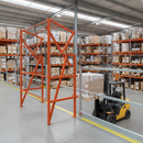 Pallet safety gate fitted to a warehouse mezzanine edge with a forklift lifting a wrapped pallet up to the opening and racking behind