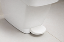 Close-up of the wide foot pedal at the base of a white sanitary bin on a washroom floor