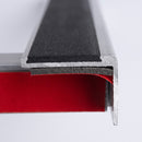 Cut end of an aluminium stair nosing showing the peel and stick adhesive tape layer on its underside
