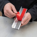 Red protective liner being peeled from the double-sided adhesive tape on the underside of an aluminium stair nosing