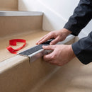 Aluminium stair nosing being bonded to a concrete step with its peel and stick adhesive backing, no screws
